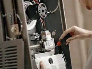 Furnace repair technician inspecting internal components and wiring in Highland Park, IL