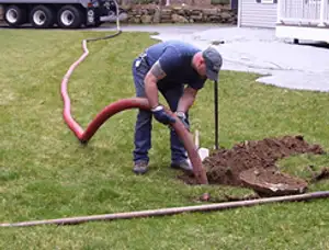 Septic pumping technician servicing a residential septic tank with a vacuum hose in Highland Park, IL