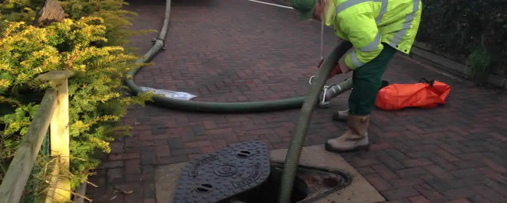 Septic tank cleaning technician servicing a septic tank with a vacuum hose in Highland Park, IL