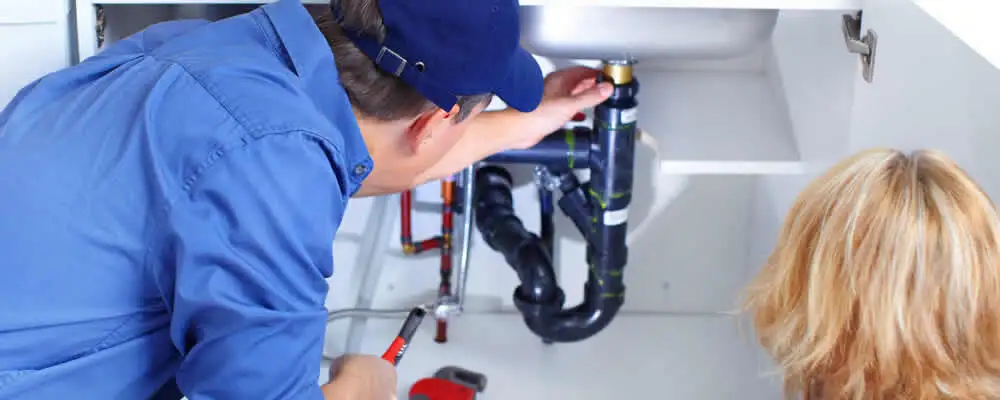Plumber repairing under-sink drain pipes and fittings in Highland Park, IL