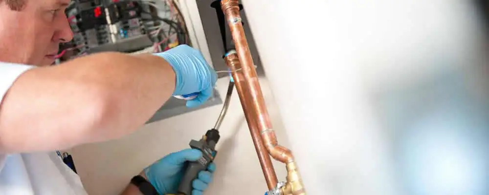Water heater repair technician testing copper pipe connections and controls in Highland Park, IL